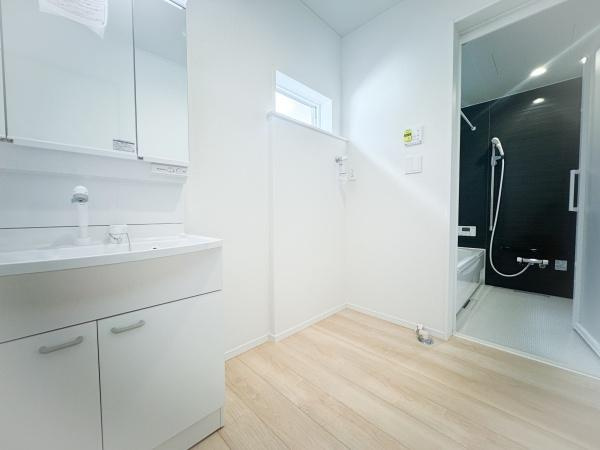 畑中第1-2号棟の独立洗面台|洗面台・洗面所は白を基調とした清潔感のある空間です。床の木目調が明るい雰囲気を演出します。洗面台は収納も備えており使いやすさに配慮されています。お風呂までの動線もスムーズです。