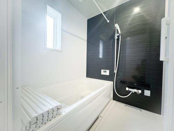 畑中第1-2号棟の浴室|シンプルで清潔感のあるバスルームです。窓があり換気もしやすい造りです。ブラックのアクセントパネルが空間にメリハリを与えています。浴槽は使いやすいサイズ感です。浴室乾燥も可能です。