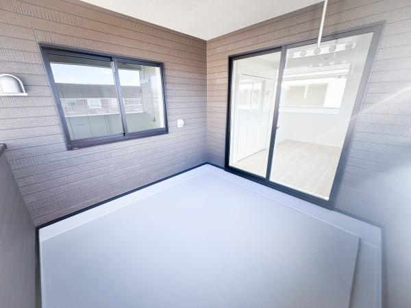 畑中第1-2号棟のバルコニー|バルコニーは広々とした空間で使い方の幅が広がります。窓とスライドドアがあり室内との行き来も快適です。壁面の落ち着いた色合いが特徴的です。明るさも確保されており外からの光がしっかり入ります。