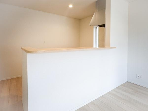 畑中第1-2号棟のキッチン|シンプルで落ち着いたデザインのキッチンです。カウンターがあり空間を広く使えます。明るい色合いの床と壁が清潔感を感じさせます。コンロ周りには換気フードが設置されています。