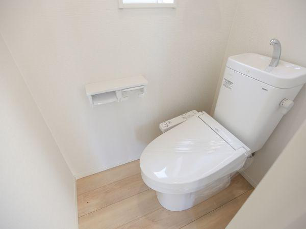 横田第2-2号棟のトイレ|シンプルで清潔感のあるトイレです。ホワイトを基調とした内装が明るい印象を与えます。床は木目調でお手入れもしやすそうです。窓が設置されており換気にも配慮されています。