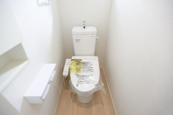 徳島第6-1号棟のトイレ|明るい雰囲気のトイレです。小窓があるため換気がしやすく空間も清潔感にあふれています。収納スペースも設けられており使いやすい設計です。壁紙や床材がシンプルで落ち着いた印象です。