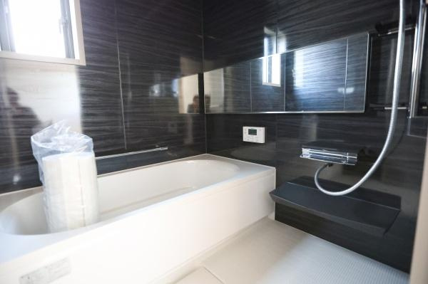 AG-HOUSE　ゆめが丘　B棟の浴室|シックな壁面デザインが特徴のバスルームです。大きなミラーが空間を広く感じさせます。窓があり換気しやすいのもポイントです。使いやすいカウンター付きで機能性にも配慮されています。