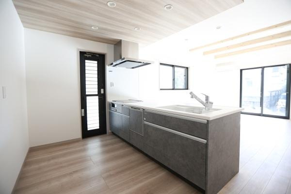 AG-HOUSE　ゆめが丘　A棟のキッチン|開放感のあるキッチンが印象的です。木目調の天井と床が空間を引き締めスタイリッシュなデザインが魅力です。収納スペースも充実しているので整理整頓に便利です。大きな窓から光が差し込み室内が明るくなります。