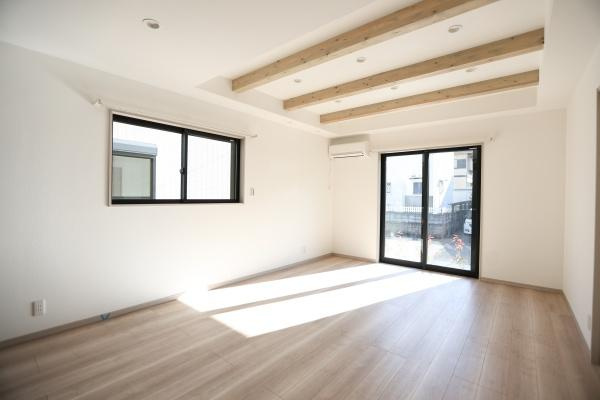 AG-HOUSE　ゆめが丘　A棟の居間・リビング|明るい光が差し込むリビングは天井の梁がアクセントとなっています。ナチュラルなフローリングが空間を引き立てます。大型の窓とバルコニーへのアクセスも便利です。