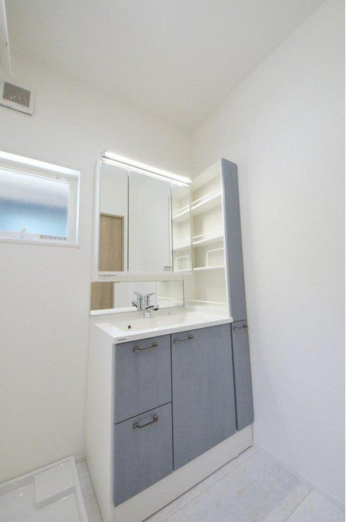 中山新町1丁目の洗面所|清潔感あふれる白を基調としたシャワー付洗面台と洗面室。収納棚もある余裕のスペース。窓もあり明るく通気も良いです。