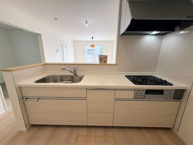 クレイドルガーデン糸満市大度 第1・２号棟のキッチン|コミュニケーションの取りやすい対面式のキッチン／リビングの眺め