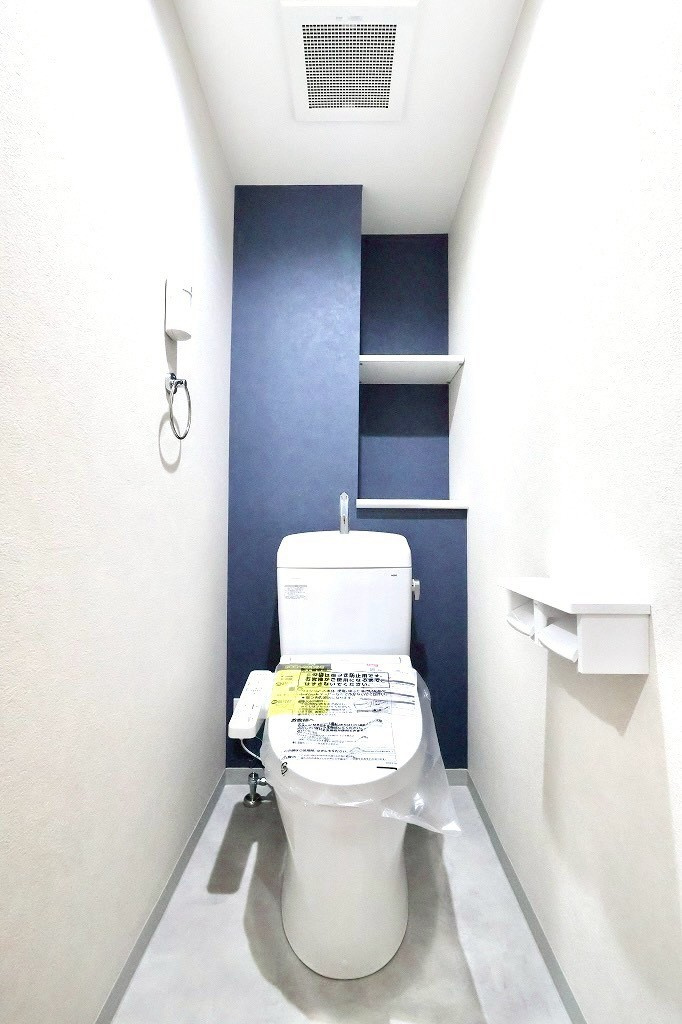 モリスガーデンヒルズ井土ヶ谷のトイレ|落ち着いたネイビーカラーのアクセント壁が上質な雰囲気を演出。収納棚も備わり、使い勝手とデザイン性を両立した清潔感あるトイレ空間です。