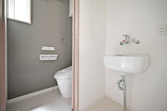 ハッピータウン伊丹市池尻6丁目新築一戸建て│3SLDK+t駐車1台可のトイレ|2階トイレの内観写真です。アクセントクロスを採用した高級感あふれる空間に仕上がっています。トイレ入口横には手洗い器が設置されています。