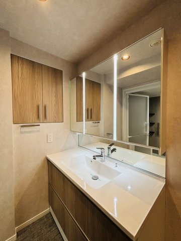 ３面鏡付き洗面台。縦のラインの照明がスタイリッシュ。