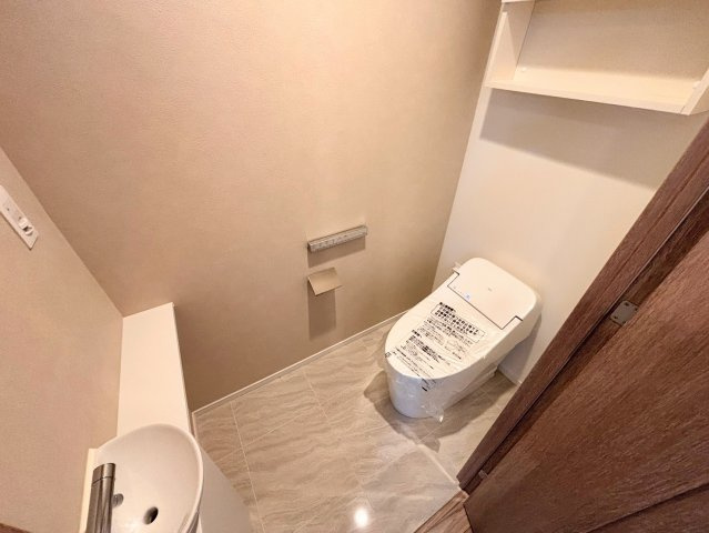 清潔感あふれるタンクレストイレを採用し、空間を広々とスマートに演出。便利な手洗いカウンターも備わっており、ゲストへの配慮も行き届いた設計です。上部の棚はストック品の収納に重宝します。