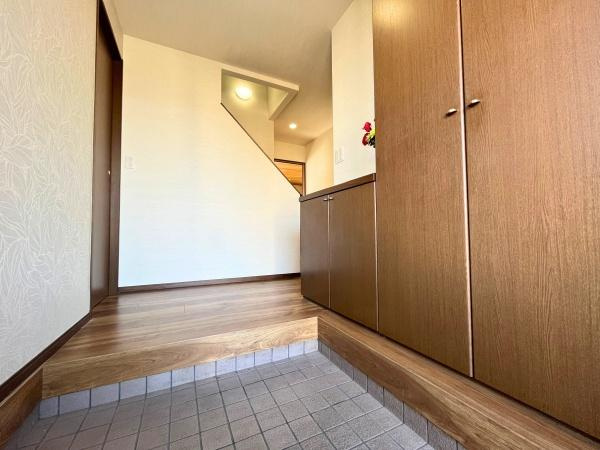 判田台南3丁目　戸建の玄関|木目調の収納が調和した玄関スペースです。段差が明確でタイルとフローリングの切り替えが印象的です。収納も豊富で使いやすさが感じられます。