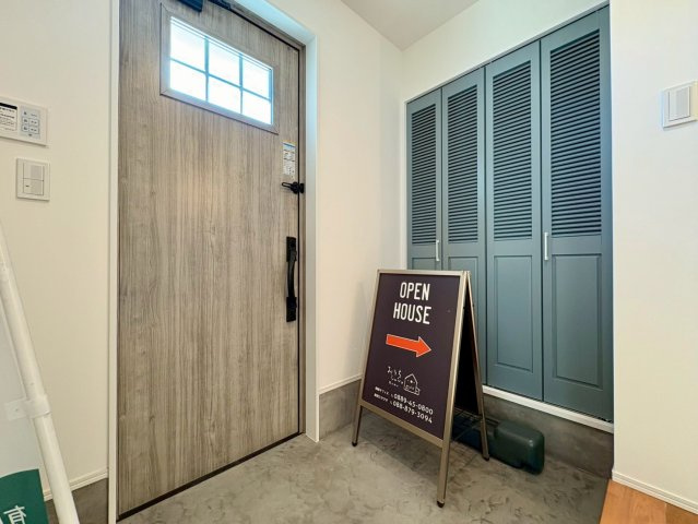 南国市大そね甲　中古一戸建ての玄関|木目のドアとグレーの収納扉が調和する玄関ホール。広めの土間スペースでベビーカーやアウトドア用品も置きやすく、暮らしやすいお家です♪