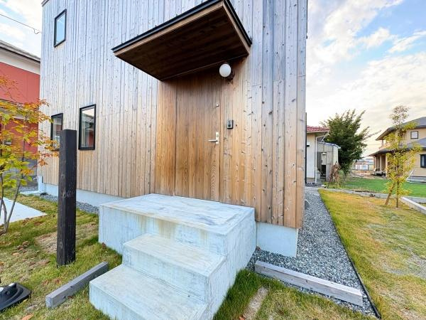 つのこばるヴィレッジ　Ｂ棟の玄関|シンプルで洗練された木目調の外観が魅力的な玄関です。直線的なデザインが印象的で落ち着いた雰囲気を感じられます。玄関ポーチには屋根があり雨天時の出入りも安心です。