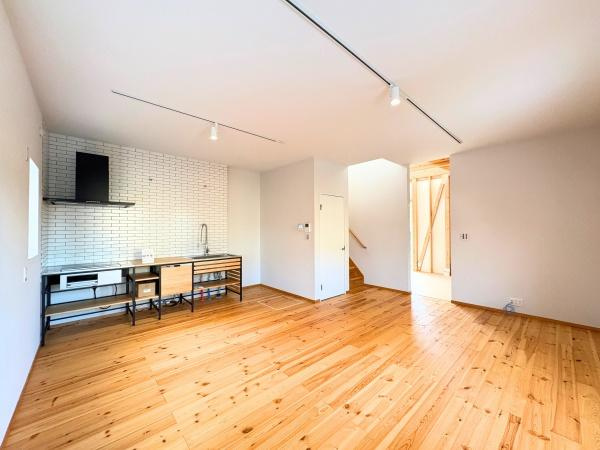 つのこばるヴィレッジ　Ｂ棟の居間・リビング|木目の美しさが引き立つリビングです。開放感のある空間が広がっており、キッチンと一体感のあるデザインが特徴的です。シンプルな壁面がインテリアのアレンジを楽しめます。