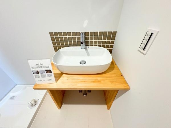 つのこばるヴィレッジ　Ｂ棟の独立洗面台|シンプルで清潔感のある洗面台が設置されています。ナチュラルな木目のカウンターが明るい印象です。タイルのアクセントが周囲と調和し空間にメリハリを与えています。