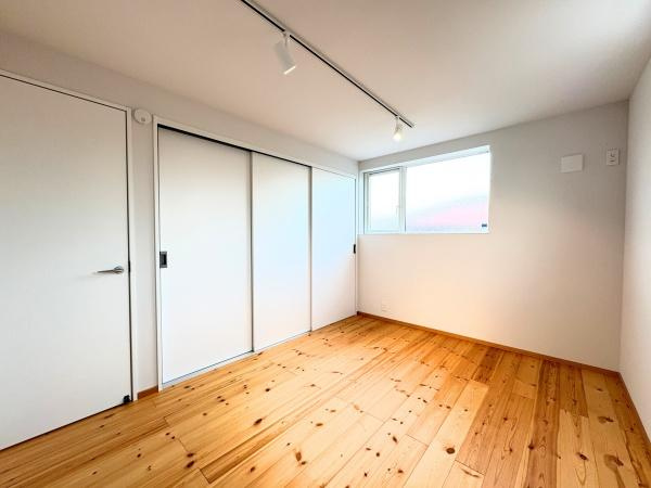 つのこばるヴィレッジ　A棟の洋室|明るい日差しが差し込むリビングです。ナチュラルな木目フローリングが特徴的です。シンプルな白壁とスライドドアで空間がすっきりと仕上がっています。天井のスポットライトもアクセントになっています。