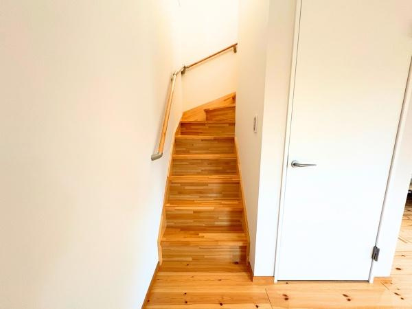 つのこばるヴィレッジ　A棟の内装|明るい色合いの木材を使用した階段が室内に温かみを加えます。手すりも設置されており安心して利用できる仕様です。スペースを有効活用した直線型の設計です。白い壁と木目のコントラストも魅力です。