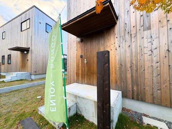 つのこばるヴィレッジ　A棟のその他|木目調の外観が印象的な建物です。シンプルな玄関まわりが落ち着いた雰囲気を演出しています。段差のあるアプローチが空間にアクセントを加えています。