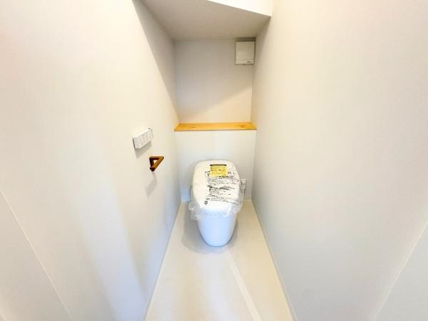 つのこばるヴィレッジ　A棟のトイレ|白を基調とした内装で清潔感のあるトイレです。奥には小物を置けるカウンターが設置されています。機能的な設備が整っており空間にゆとりがあります。