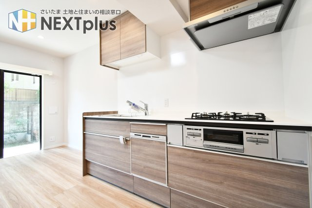 ライオンズマンション大宮堀の内のキッチン|木目基調の吊戸棚付きシステムキッチンです。上にも下にもたくさん収納出来ますので、別途で食器棚がなくてもたくさん収納する事ができます！ライトもありますので、お料理中の手元もしっかり照らしてくれます。