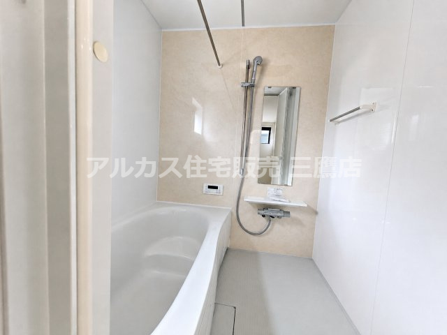 西東京市向台町2丁目 西武新宿線 田無駅 新築戸建ての浴室|木目調のアクセントパネルが柔らかな雰囲気を演出するユニットバス。シャワーバーや鏡、浴室乾燥機用のランドリーパイプが整っています。