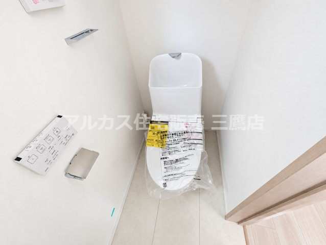 西東京市向台町2丁目 西武新宿線 田無駅 新築戸建てのトイレ|1階の温水洗浄便座付きトイレ。清潔感のある白を基調とした空間で、壁面にはリモコンやペーパーホルダー、タオル掛けがすっきりと配置されています。