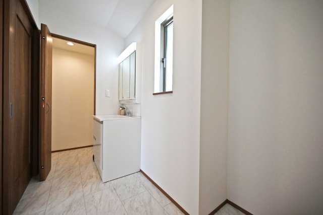 ハートフルタウン伊丹荻野4丁目新築一戸建ての洗面所|洗面室は白を基調とした空間で清潔感があります。洗面台の奥はファミリークロークとなっております。