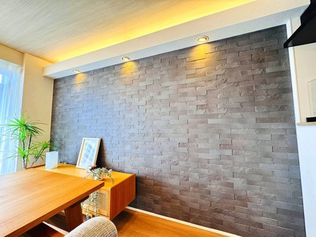 【居間・リビング】 | パーク・エステート上板橋（成増店） | リビングの一部にデザイン性と機能性（調湿・脱臭）を備えた壁材「エコカラット」を採用。上部のダウンライトと合わせリビングの雰囲気をより一層高めています。※画像の家具・小物等は販売対象に含みません。