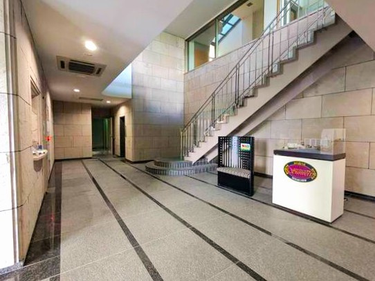 サンヴェール伊東オーシャンビューのエントランス|石張り床のエントランスホールにストレート階段も見える