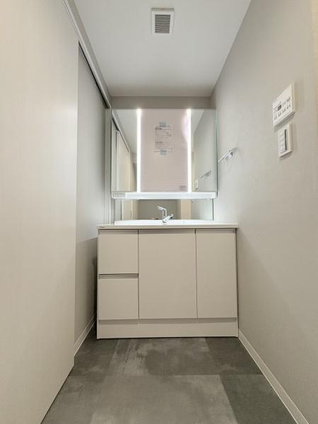 サングレイスパセオ・デラルスの独立洗面台|パナソニック製、洗面化粧台・グレーの床に生えるホワイトピンクで温かみのある洗面に。収納も充実。三面鏡なのでついやすいですね。