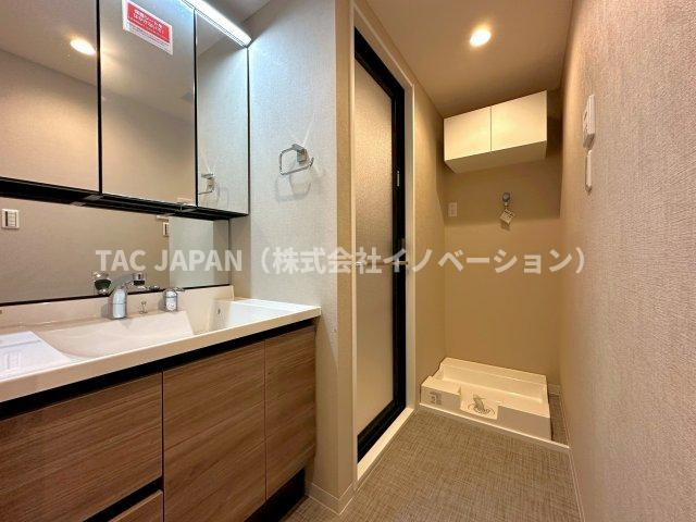 エバーグリーンパレス浅草の洗面所|大型の洗濯機を置いても余裕が感じられる脱衣スペースにはお洒落な洗面ユニットを制作。キッチンスペースにも直接抜けられ家事効率も大幅UP。