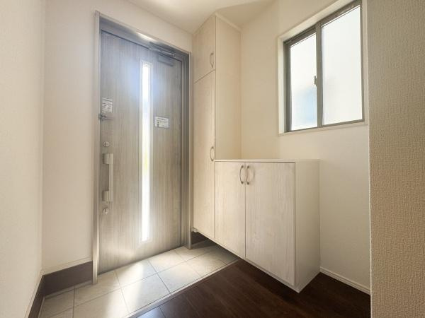 小中島3丁目1期2号棟の玄関|すっきりとした玄関スペースが印象的です。奥に収納スペースがあり、明るい照明で開放感が感じられます。