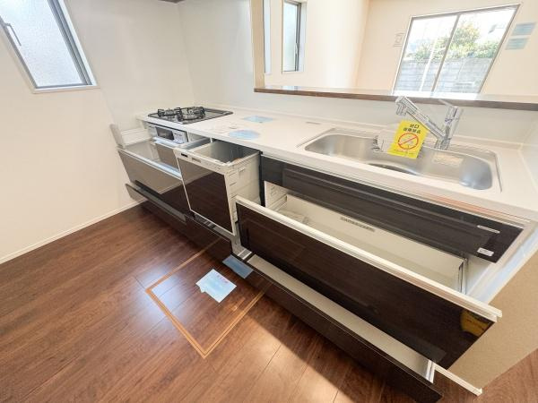 小中島3丁目1期2号棟のキッチン|広々としたキッチンは収納スペースが豊富で整理しやすい造りです。明るい照明と木目調の床が空間を引き立てています。シンプルながら機能的な設備も揃っています。