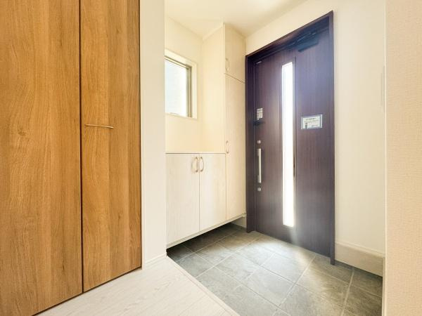 小中島3丁目1期1号棟の玄関|玄関には明るい窓があり空間全体に開放感を感じます。収納スペースも備わっており靴や小物を整理しやすい造りです。木目調のドアが印象的で室内全体が落ち着いた雰囲気となっています。
