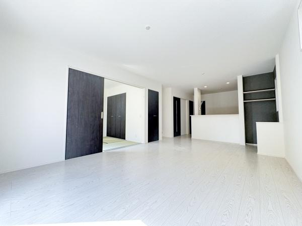 大字小池原1期3号棟の居間・リビング|リビングは白を基調とした明るい空間に仕上がっています。引き戸で隣接する和室とつながり広がりを感じられます。収納やカウンターがシンプルにまとめられています。床は木目調のデザインで清潔感があります。