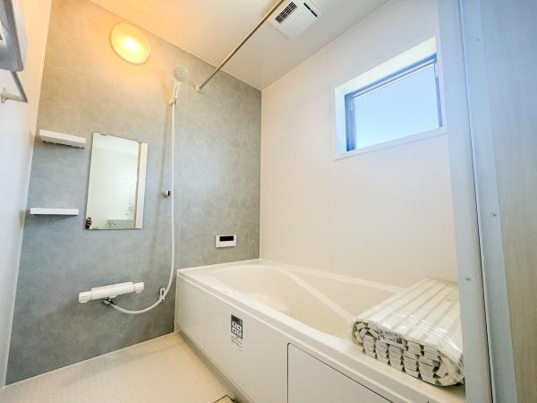 大字小池原1期2号棟の浴室|明るい窓付きで自然光が入るバスルームです。手すりが設置されており安心してご利用いただけます。シンプルで清潔感のある内装です。