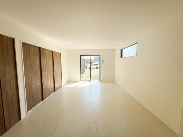 大字小池原1期2号棟の居間・リビング|リビングはナチュラルな色合いで統一され明るい光が差し込む空間です。大きな窓からは外の景色が楽しめます。壁一面のクローゼットが収納力を高めています。シンプルで使いやすいレイアウトです。