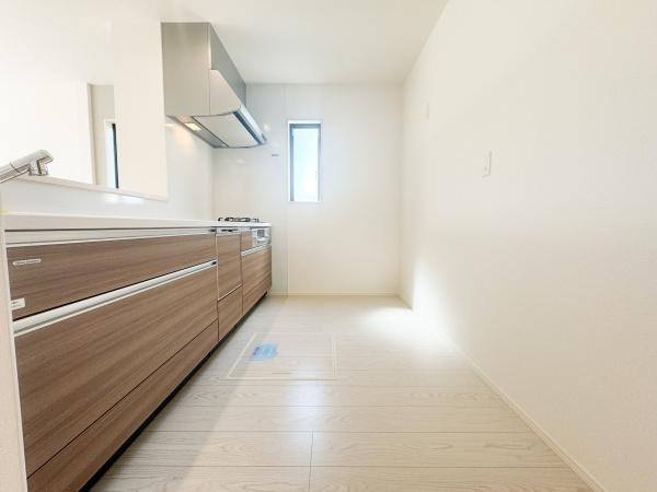 大字小池原1期2号棟のキッチン|明るく清潔感のあるキッチンです。木目調のデザインが空間にやわらかさを与えています。窓から自然光が入り作業スペースも広々としています。シンプルなレイアウトで日常の使い勝手にも配慮されています。