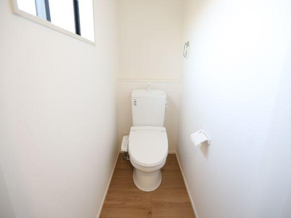 大字光吉4期2号棟のトイレ|白を基調とした内装で清潔感が感じられるトイレです。床は木目調で落ち着いた雰囲気が広がります。小窓があり自然光が入りやすい空間です。シンプルな設計で日々の使用に便利です。
