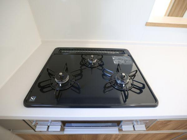 大字光吉4期2号棟のキッチン|シンプルなデザインが特徴の三口ガスコンロです。お手入れがしやすいフラットな天板が印象的です。スペースを有効活用できる配置となっています。キッチン空間がすっきりとまとまります。