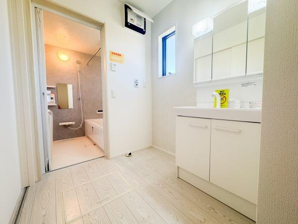 大字小池原1期1号棟の独立洗面台|白を基調とした洗面台・洗面所は清潔感のある空間に仕上がっています。大きな鏡や収納が備わっており機能性もしっかりとしています。床面のカラーとデザインが明るい印象を演出しています。