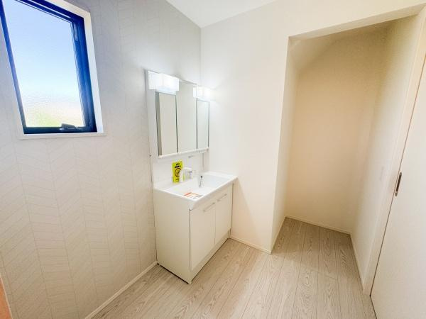 大字小池原1期1号棟の独立洗面台|洗面台は広々としたスペースに設置されており明るい照明が快適な空間を演出しています。窓から自然光が差し込み清潔感のある内装が特徴です。収納も備わっており日々のメンテナンスがしやすい仕様です。