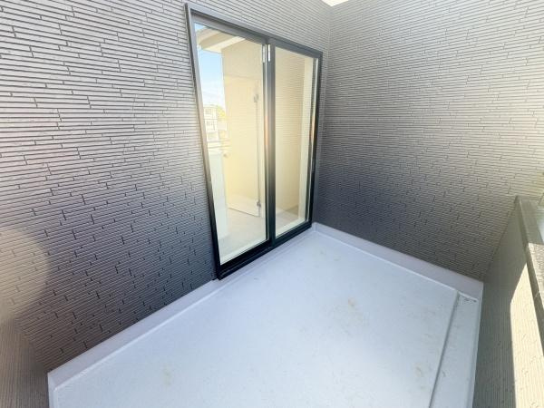 大字小池原1期1号棟のバルコニー|シンプルなデザインが特徴のバルコニーです。ゆとりのある空間でさまざまな用途にご活用いただけます。開放的なガラスドアが室内への採光をサポートします。外壁の模様がアクセントとなり印象的な雰囲気です。