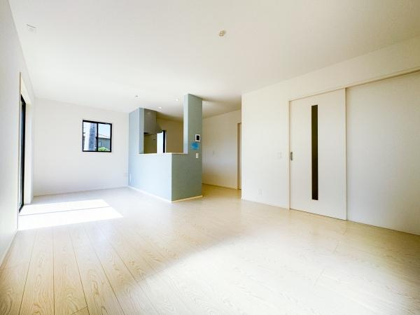 大字小池原1期1号棟の居間・リビング|リビングは大きな窓から明るい日差しが差し込み開放感のある空間です。ナチュラルなフローリングが空間全体をすっきりと見せています。キッチンとの仕切りもすっきりとした印象です。