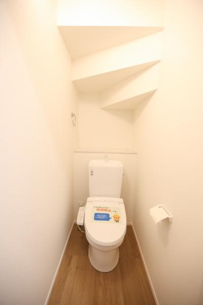 徳島2丁目1期2号棟のトイレ|シンプルで清潔感のあるトイレ空間です。ホワイトを基調とした内装が落ち着いた印象を与えます。木目調のフロアが温かみを感じさせます。限られたスペースを有効活用した設計です。収納スペースも備わっています。