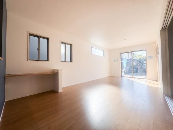 徳島2丁目1期2号棟の居間・リビング|リビングは広々とした空間で陽当たりも良く心地よさを感じられます。木目調のフローリングが温かみのある印象を与えます。白い壁と青いアクセントウォールのバランスが落ち着いた雰囲気を演出しています。