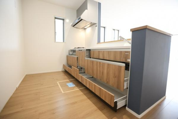 徳島2丁目1期2号棟のキッチン|木目調のデザインが温かみを感じさせるキッチンです。作業スペースが広く収納も豊富に備わっています。3口コンロが設置されており調理の効率的なレイアウトが魅力です。