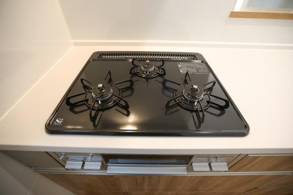 徳島2丁目1期2号棟のキッチン|複数の窓があるため明るさと換気が確保しやすいキッチンです。木目調の収納が空間をすっきりと見せます。シンクやコンロ周りも広々としています。収納スペースが多く整理整頓がしやすい仕様です。