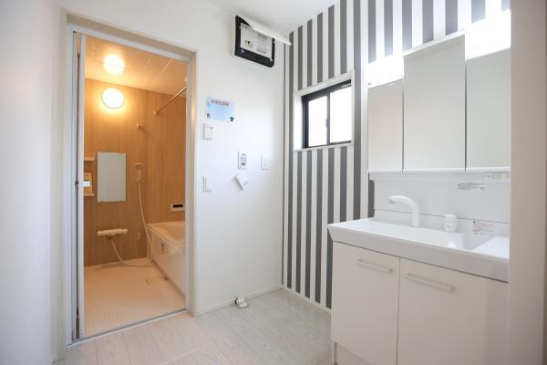 横尾東町1丁目1期2号棟の独立洗面台|洗面所はシンプルで清潔感のある印象です。ホワイトを基調とした洗面台が空間を明るく見せます。ストライプ柄の壁がアクセントとなり個性的な雰囲気を演出しています。